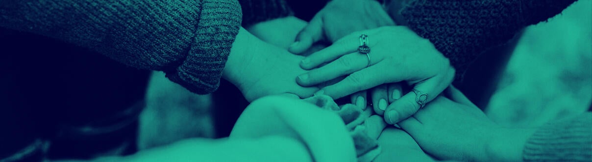 Group of people with their hands in a pile in the middle